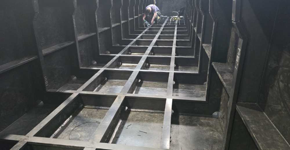 Shell showing the floor and ribs. You can also see some welding being done towards the stern.